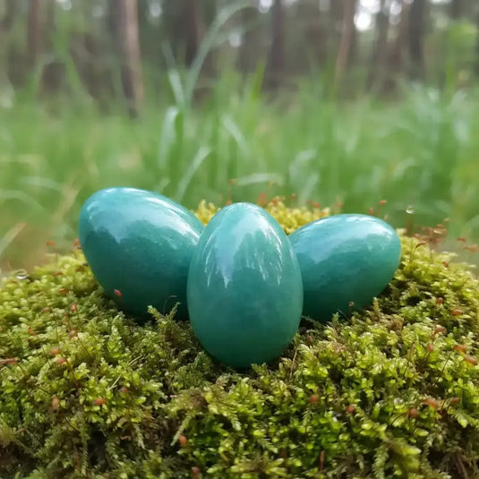 Œuf Tantra Yoni en Aventurine verte sur tapis de mousse fraiche et forêt en arrière plan