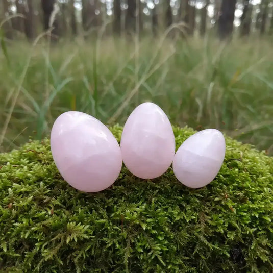 Œuf Tantra Yoni en quartz roses , sur tapis de mousse fraiche et forêt en arrière plan