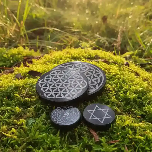 Diverses plaques de Géométrie sacrée posée sur tapis de mousse fraiche et forêt en arrière plan