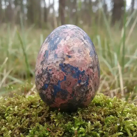 Œuf Tantra Yoni en Jaspe léopard, sur tapis de mousse fraiche et forêt en arrière plan