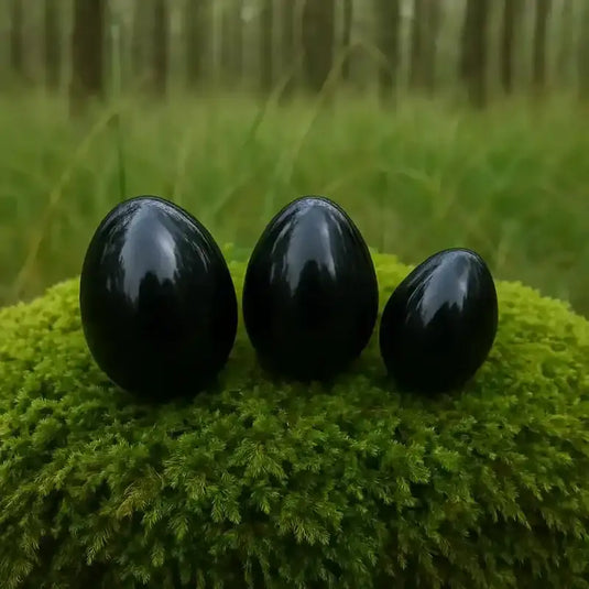 Œuf Tantra Yoni en Obsidienne noire, sur tapis de mousse fraiche et forêt en arrière plan